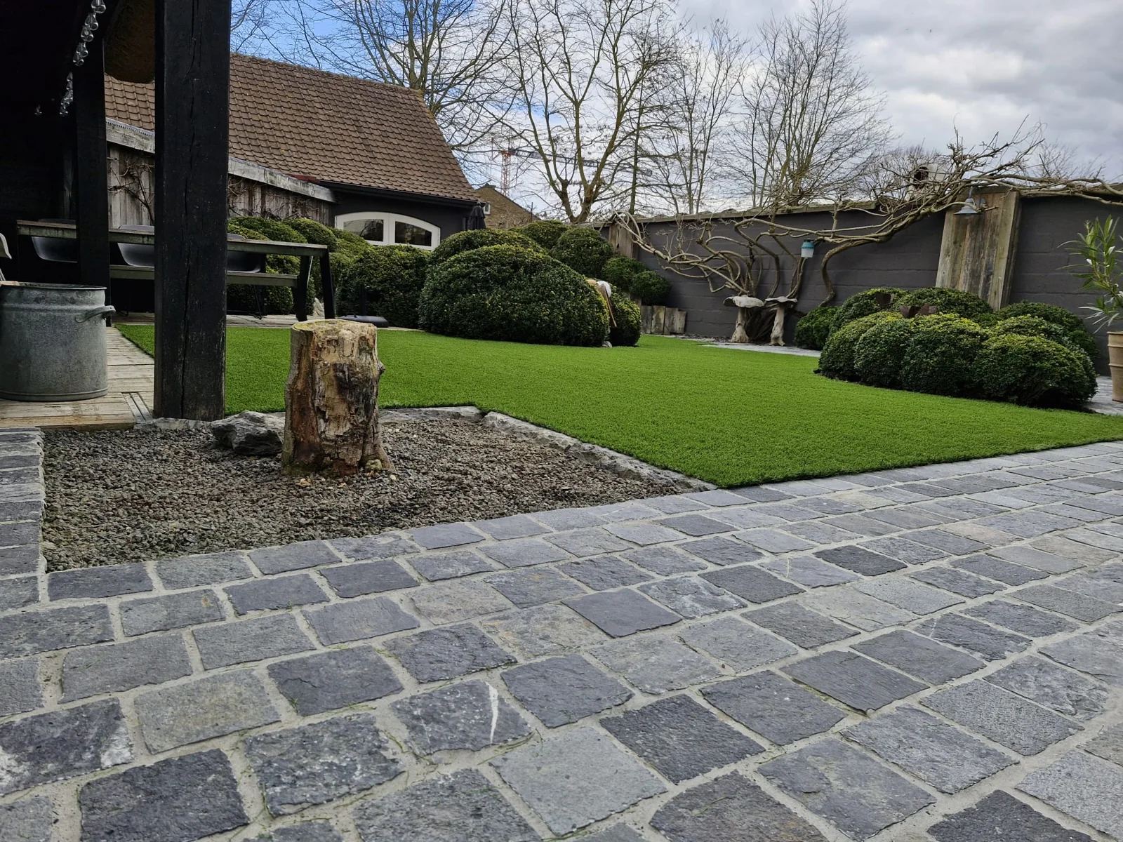 Afgewerkte kunstgrastuin in Menen met afgeronde borders en kasseipad
